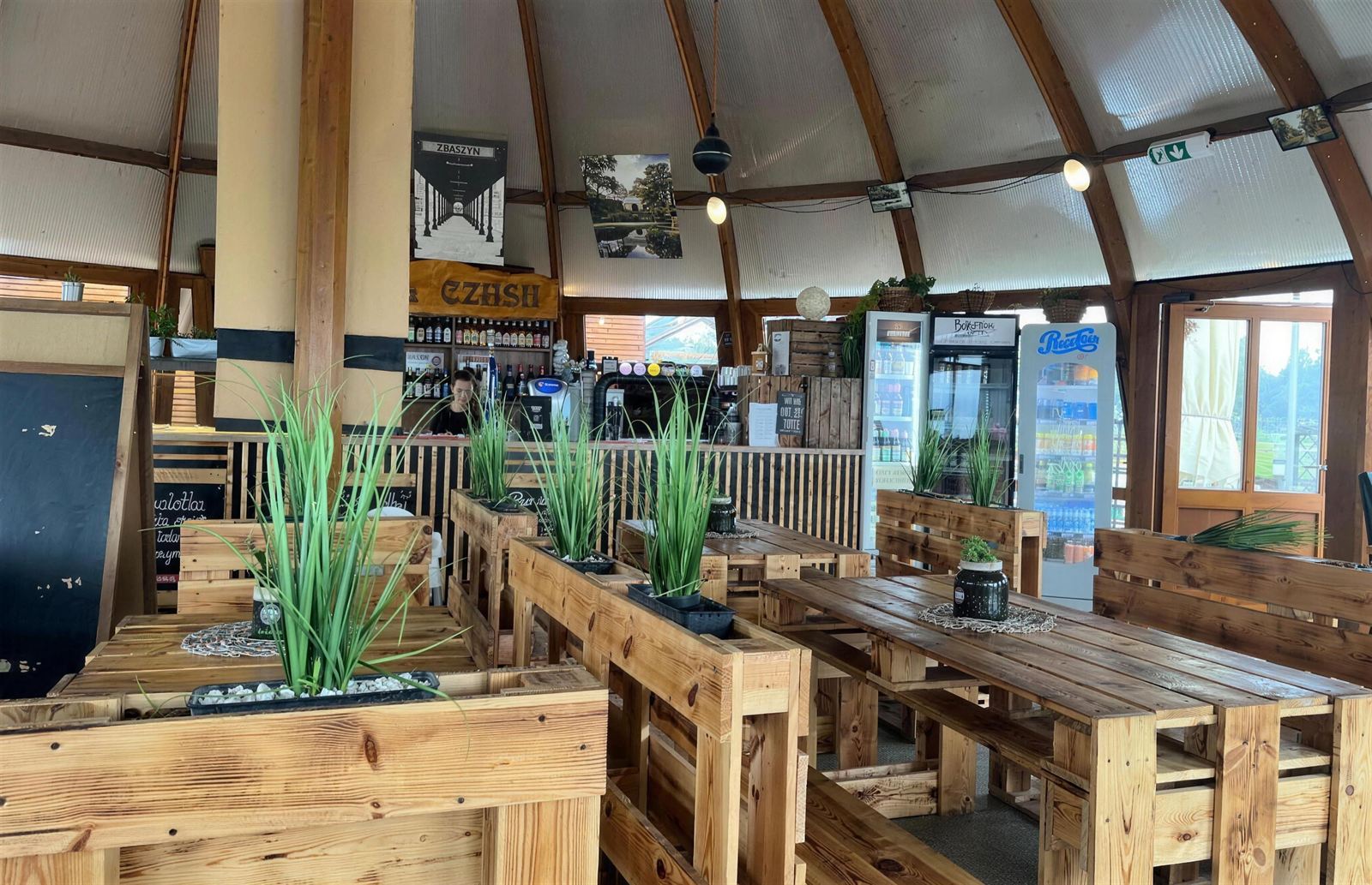 Wnętrze kopuły grzybka – drewniany bar i stoły z palet
